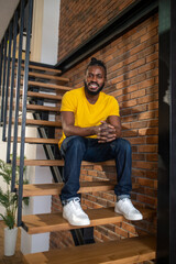 Obraz na płótnie Canvas Man sitting on stairs smiling at camera