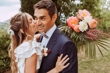 Beautiful wedding couple portrait. Bride kissing husband cheek.