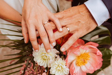 Obraz na płótnie Canvas Close up portrait of wedding couple hands with rings and flower bouquet. 