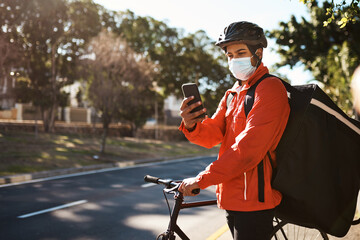 Trying to find his way to the next delivery point. Shot of a masked man using his cellphone while...