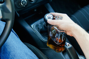 Close up of man driving car and holding bottle of alcohol. Responsibly and safety driving.