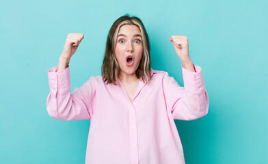 pretty caucasian woman celebrating an unbelievable success like a winner, looking excited and happy...