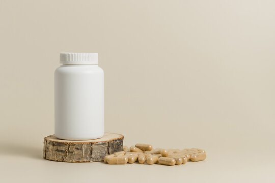 Mockup bottle on wooden stand with natural bio pills or vitamins, beige background. White bottle with healthy supplement