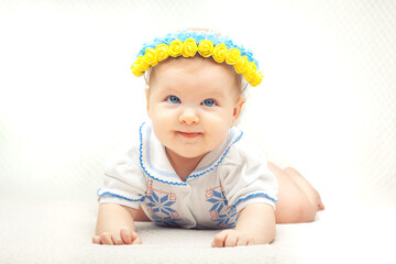 baby with flower wreath in the colors of the Ukrainian flag. six month old blue-eyed girl dressed in a national embroidered shirt