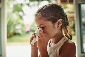 Shes feeling under the weather. Shot of a young girl blowing her nose.