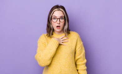 pretty caucasian woman feeling shocked, astonished and surprised, with hand on chest and open...