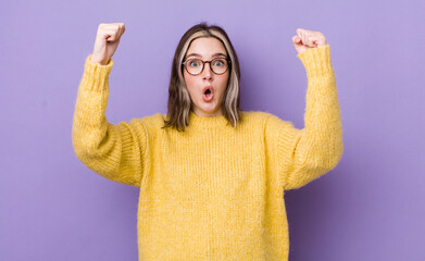 pretty caucasian woman celebrating an unbelievable success like a winner, looking excited and happy...