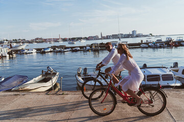 Senior couple enjoying a beautiful morning together riding a bike by the sea. Selective focus