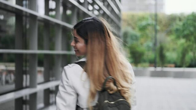 Video of elegant woman listening to music while walking on the street looking at camera at the city.