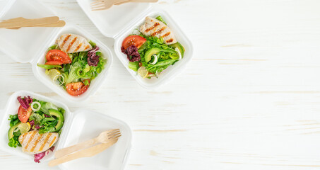 Lunch boxes with salad and chicken on white wooden table. Takeaway food. Copy space
