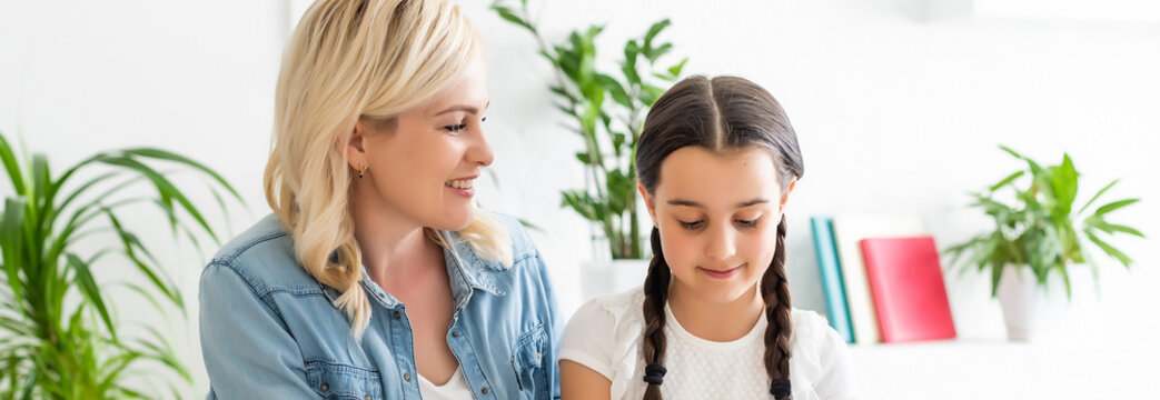 schoolgirl and mother together doing homework in home