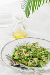 Green vegetarian salad of avocado, cucumber, seeds, micro-greens and red onion on a white background