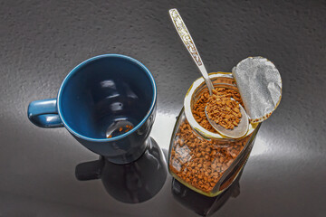 An empty coffee cup and a can of instant coffee on a black background