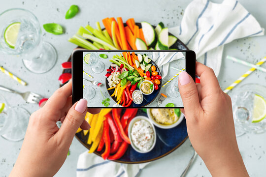 Woman taking photo of sliced vegetables with smartphone. Posting food pictures (images) on social media.
