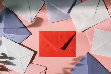 Top view of blank red envelope in the centre of frame of various envelopes.
