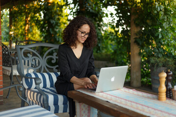 Beautiful businesswoman working on her laptop, posing on the terrace.