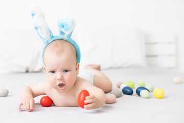 Fototapeta na wymiar Portrait of a cute baby dressed in Easter bunny ears with a basket full of eggs