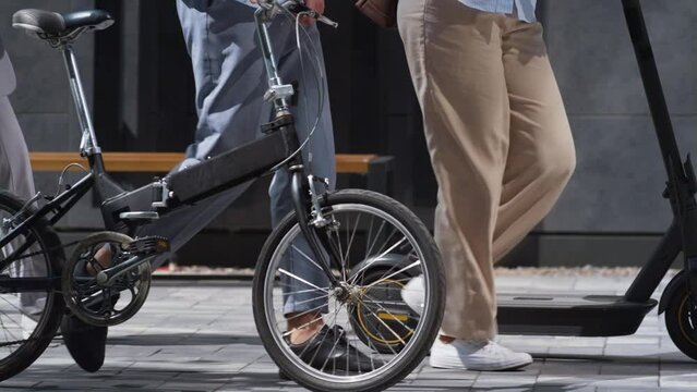 Workers legs walking downtown with electric scooter bicycle in hands close up.