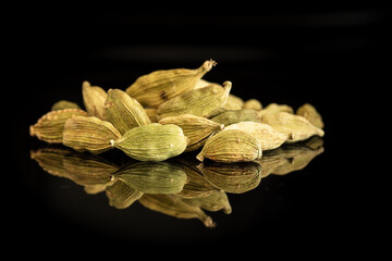 Bunch of cardamom pods reflecting on black surface