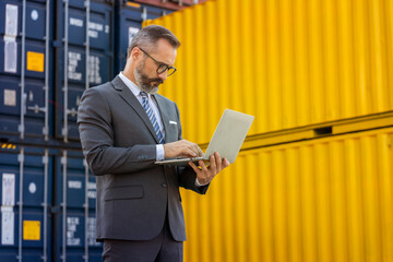 Business man holding a tablet looking at the list of export and import orders through the port...