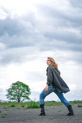 young woman in boots and jeans walking at abandonded street
