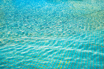 Relaxing surface of blue swimming pool, background of water. Ripples, small waves of water in swimming pool with sunny bright light. Shining blue water ripple background
