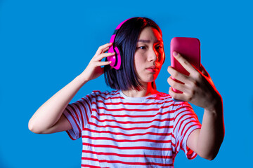Naklejka premium Young asiatic woman isolated using smartphone taking selfie