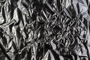 Black dark silver crumpled plastic material texture background