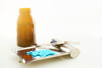 pills counting tray with spatula and round coated medicine tablets and jar on blur background with copy space