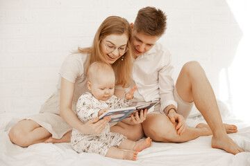Glad family spending time together, barefoot mother, father, baby. Reading book fairytale, describe...