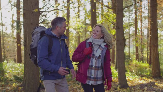 Mature couple walking through fall or winter countryside looking at navigation app on mobile phone to find way - shot in slow motion