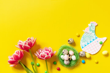 Colorful Easter background. Holiday greeting card with painted eggs and pink tulip. Top view flat lay. Copy space.