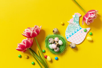 Colorful Easter background. Holiday greeting card with painted eggs, pink tulip. Top view flat lay.