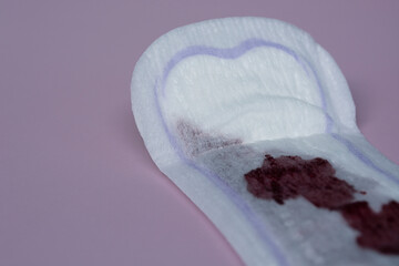 Menstrual blood on a sanitary pad on pink background. Flat lay
