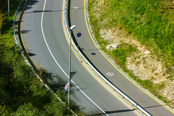 Aerial view of asphalt road turning a corner in daylight at summer day. White dividing strip,...