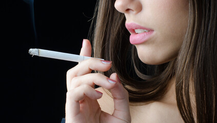 Portrait of young woman smoking cigarette isolated on black background