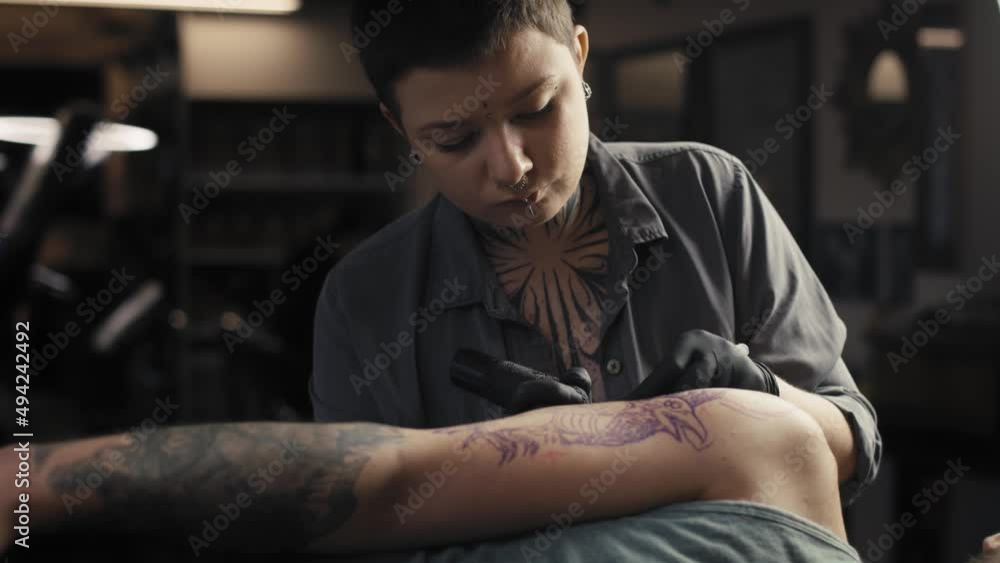 Sticker adult caucasian woman tattooing arms of her customer. shot with red helium camera in 8k.