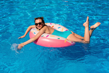 young woman in bikini swims on the inflatable water donut in the swimming pool.