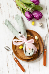 Easter table setting with painted eggs, purple tulip and cutlery on festive table. Table setting for Happy Easter day. Top view flat lay.