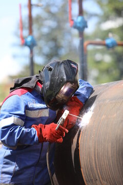 Male welder works. Welding joint of large diameter pipe. High pressure pipe welding for a gas station.