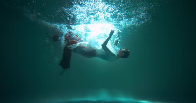 INFORMATION OVERLOAD Cinematic shot, young beautiful woman dives, slowly sinks down helplessly under water slow motion.