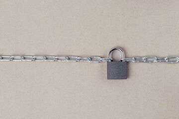The links of a metal chain are fastened with a padlock on a gray background.  Security concept
