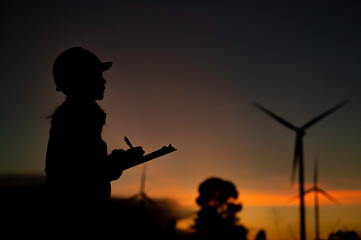 Fototapeta na wymiar Asian Man engineers working and holding the report at wind turbine farm Power Generator Station on mountain,Thailand people,Technician man at site of work