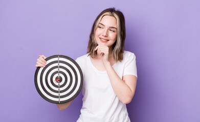pretty caucasian woman smiling with a happy, confident expression with hand on chin. dart target...