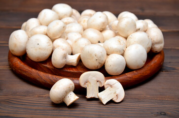 fresh champignon mushrooms whole and cut on a wooden board