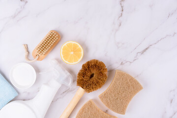 Set of natural household cleaners made of simple eco ingredients, bamboo brush, organic dishcloth, lemon, baking soda on marble background with copy space. Green cleaning concept