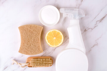 Set of natural household cleaners made of simple eco ingredients, bamboo brush, organic dishcloth, lemon, baking soda, citric acid on marble background with copy space. Green cleaning concept