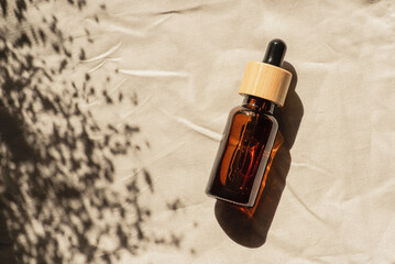 Amber glass bottles with dropper pipette with serum or essential oil on light fabric background....