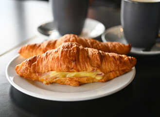 Croissant ham cheese is a France food, Croissant with ham and cheese on white plate ,and coffee.
