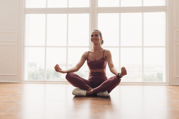 Young woman sitting in lotus position on floor